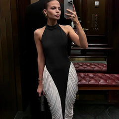 Woman taking a mirror selfie wearing a black and white dress in an indoor setting.