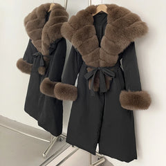 Black coat with brown fur trim on a rack against a white wall