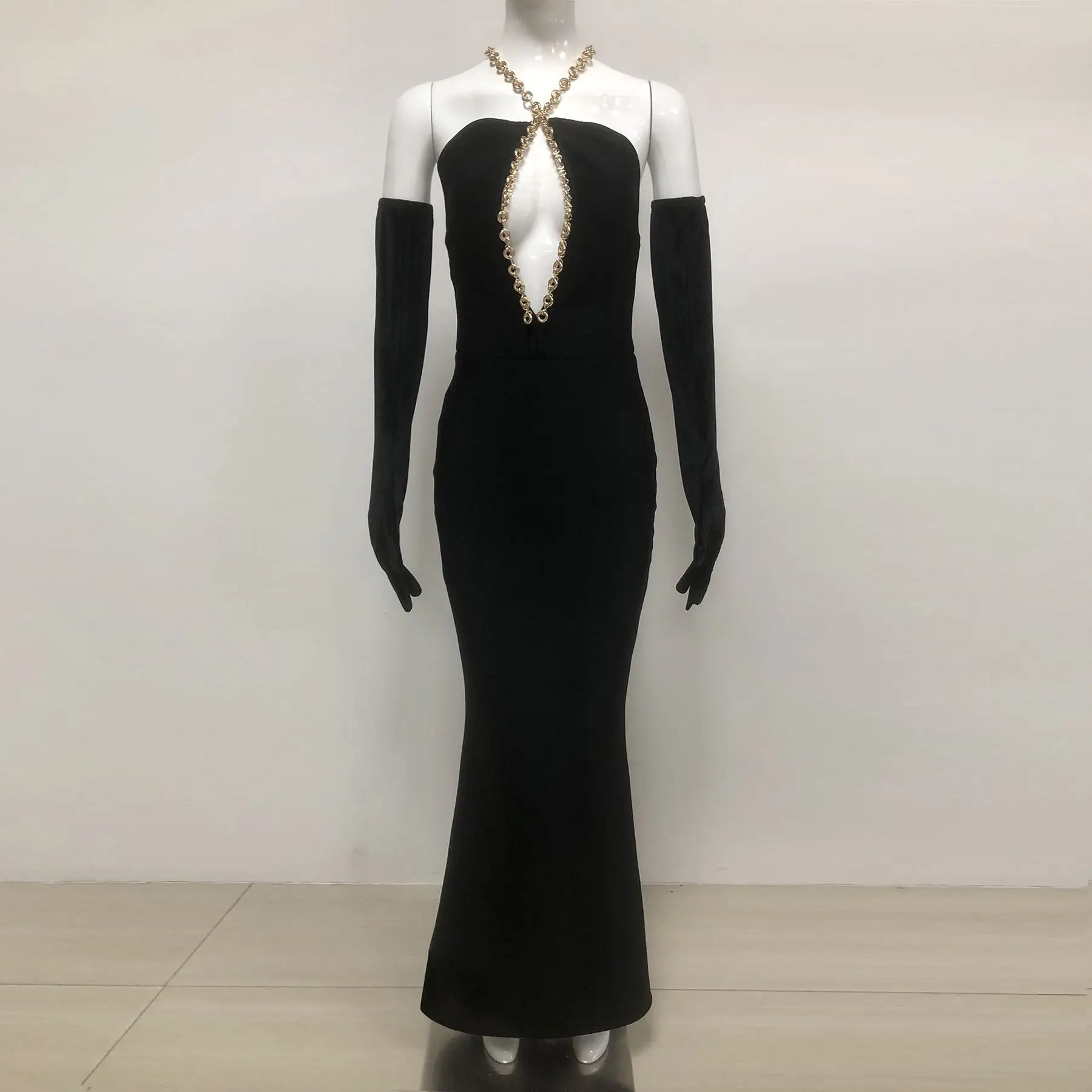 Black evening gown with gold embellishments on a mannequin against a white background