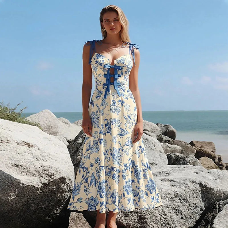 Blue floral print one-piece swimsuit and flowing skirt worn by a model on a rocky beach.