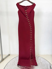 Burgundy off shoulder maxi dress with metal buckle detailing displayed on a hanger.