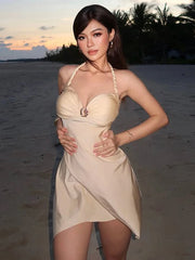 Woman in a beige dress standing on a beach at sunset
