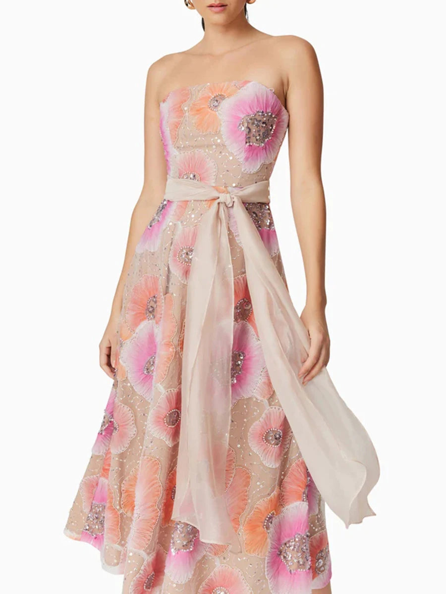 Woman wearing a strapless floral dress with embellishments on a white background