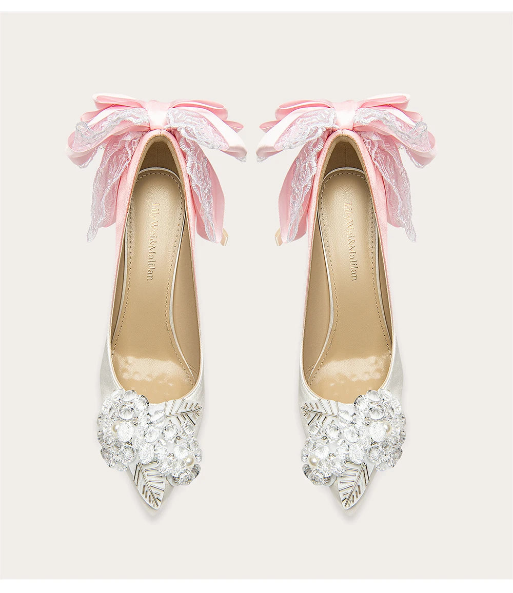 Pair of high-heeled shoes with decorative bows and embellishments on a light background