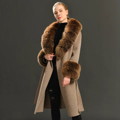Woman wearing a long coat with fur trim on a dark background