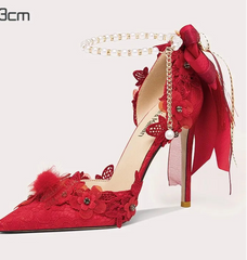 Red high-heeled shoe with floral details on a white background