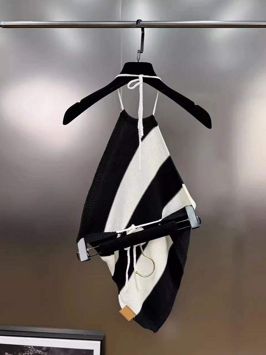 Black and white striped dress with a bow tie on a hanger against a gray background