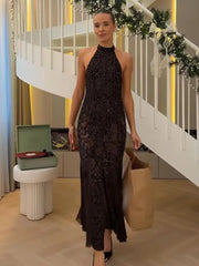 Woman in a black lace dress standing in a room with a staircase and decorative items.