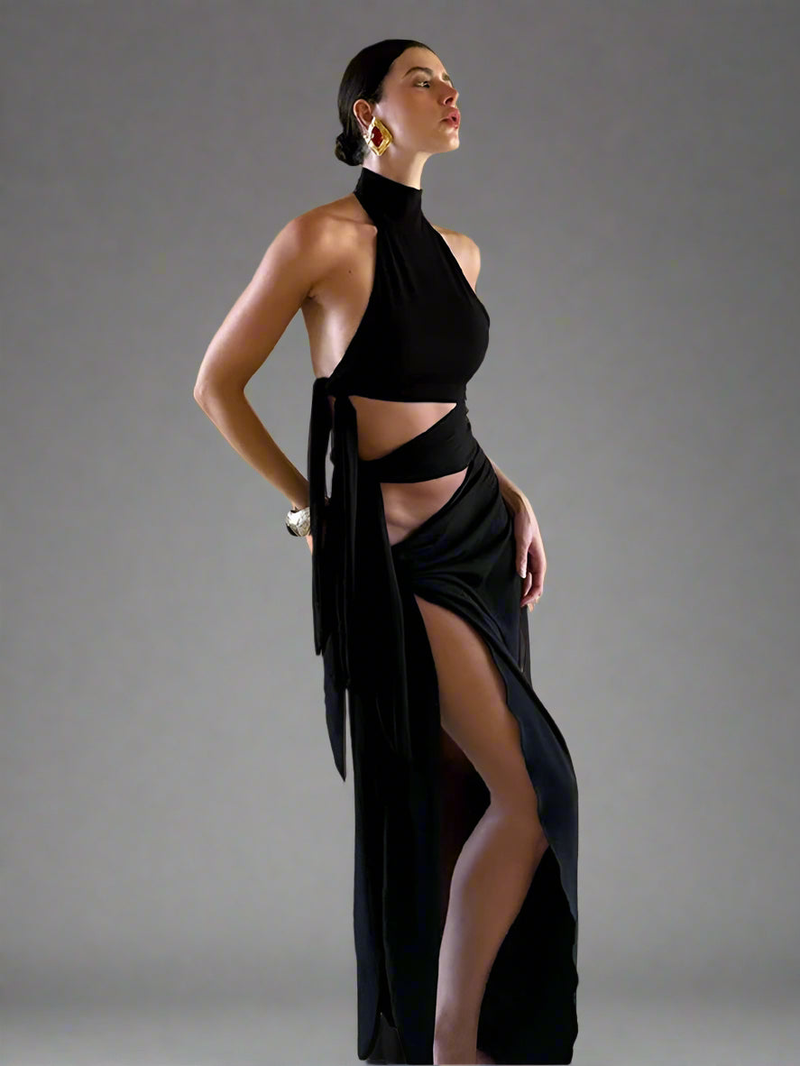 Woman wearing a black dress with a high slit in a room with beige walls.