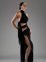 Woman wearing a black dress with a high slit in a room with beige walls.