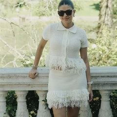 Woman wearing a white fringe dress and sunglasses, standing outdoors.