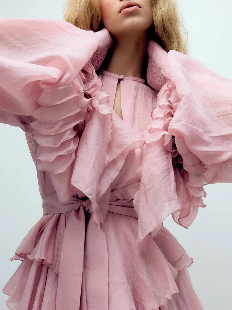 Pink ruffled dress worn by a model on a light gray background