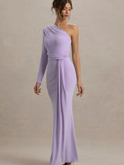 Woman wearing a one-shoulder lavender dress against a plain background