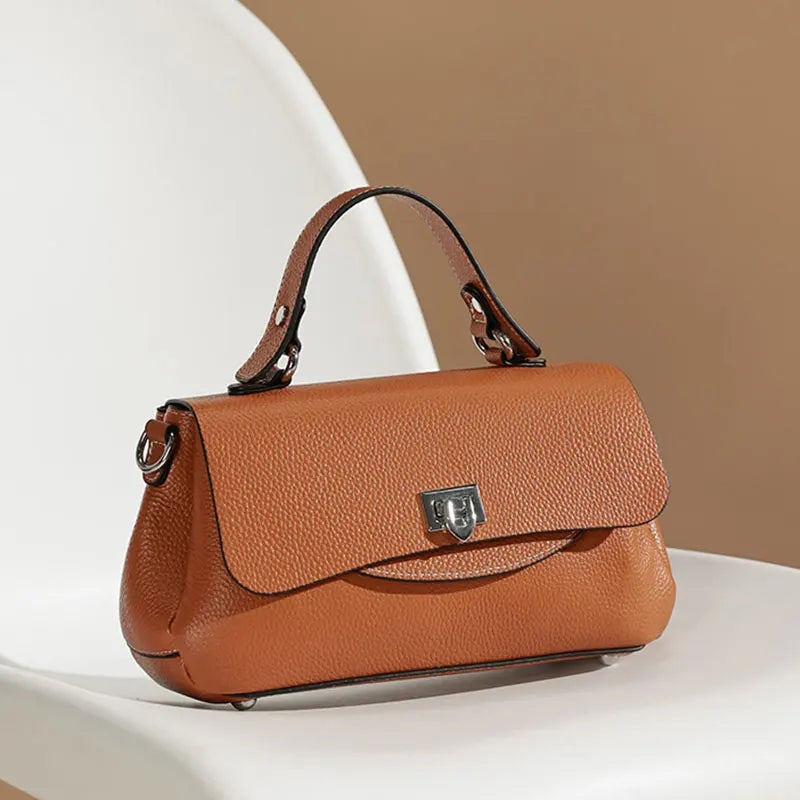 Brown leather handbag on a white surface with a beige background