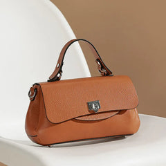 Brown leather handbag on a white surface with a beige background