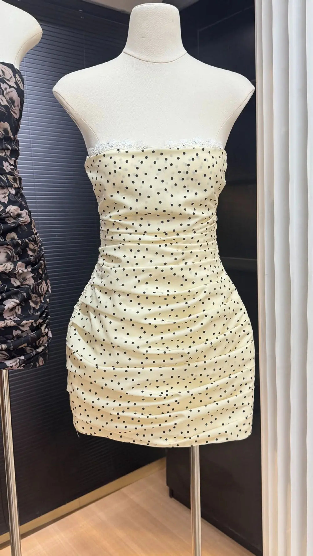 Beige strapless dress with black polka dots on a mannequin in a store setting