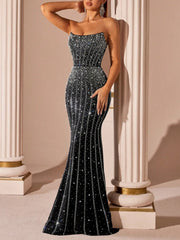 Woman wearing a sparkling black evening gown in an elegant setting.