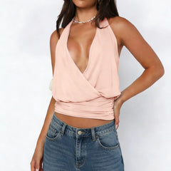 Woman wearing a light pink halter top and blue jeans on a white background