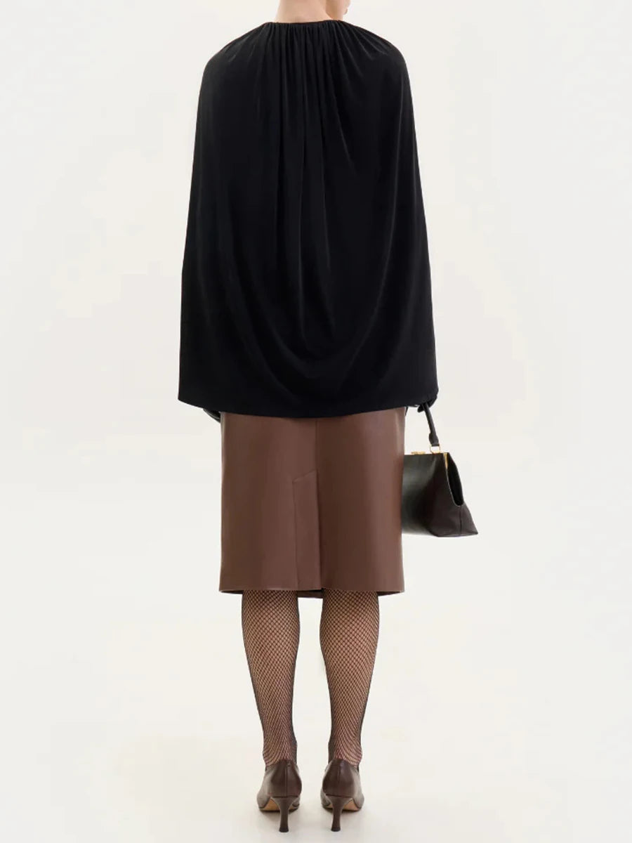 Person wearing a black top and brown skirt with fishnet tights and high heels