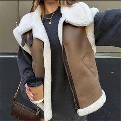 Person wearing a brown shearling jacket with white fur trim, holding a coffee cup.