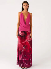 Woman wearing a deep V-neck cowl neck pink top and a floral print maxi skirt against a white background.