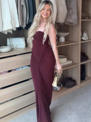 Woman in a burgundy dress standing in a room with shelves and clothing.