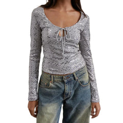 Silver sequin top with long sleeves and blue jeans on a white background