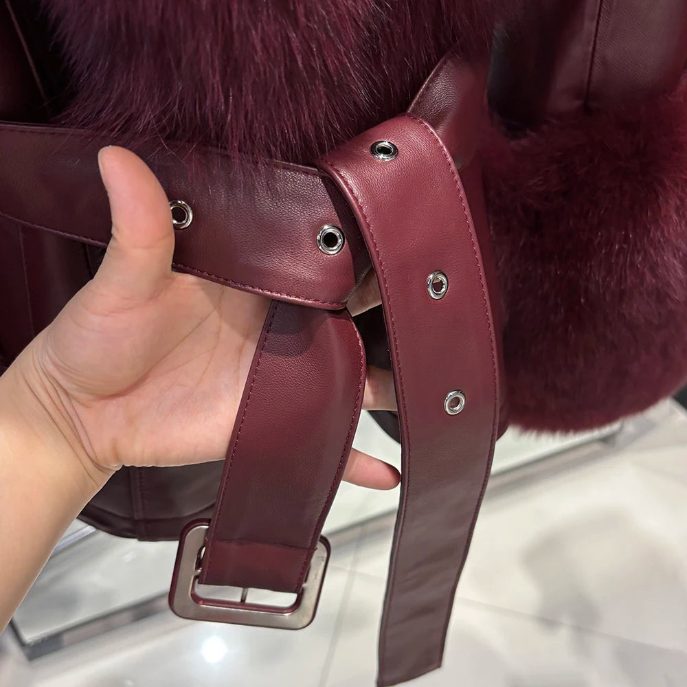 Close-up of a hand holding a burgundy leather strap with a buckle against a fur background.