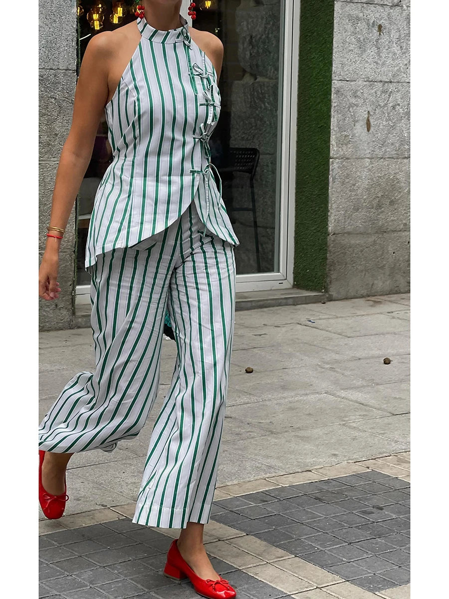 Woman wearing a green and white striped outfit with red shoes on a city street.