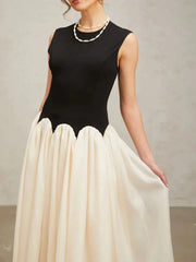Black sleeveless top with a long cream skirt against a neutral background