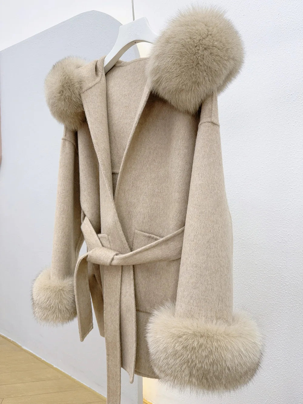 Beige coat with fur pom-poms on a white background