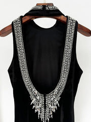 Black sleeveless top with decorative white stones on a wooden hanger against a white background