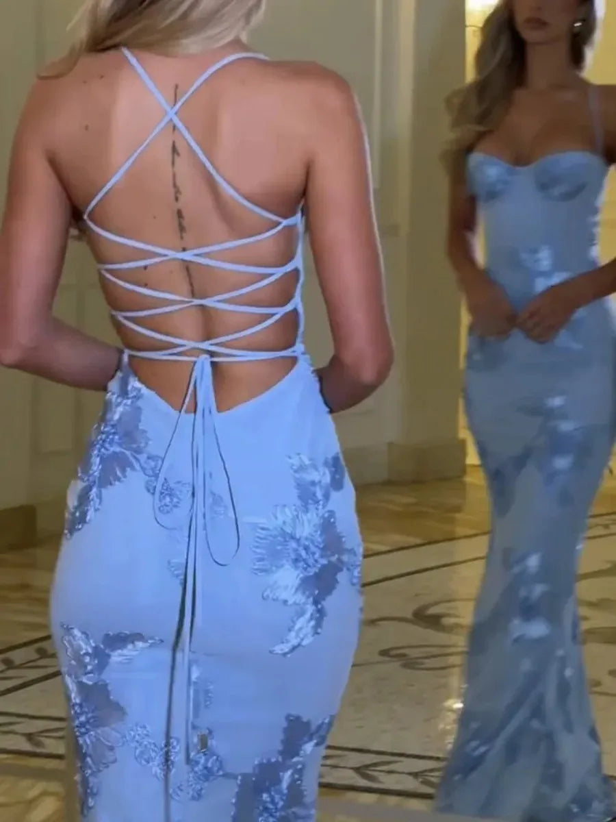 Woman wearing a light blue evening gown with floral patterns in a room.