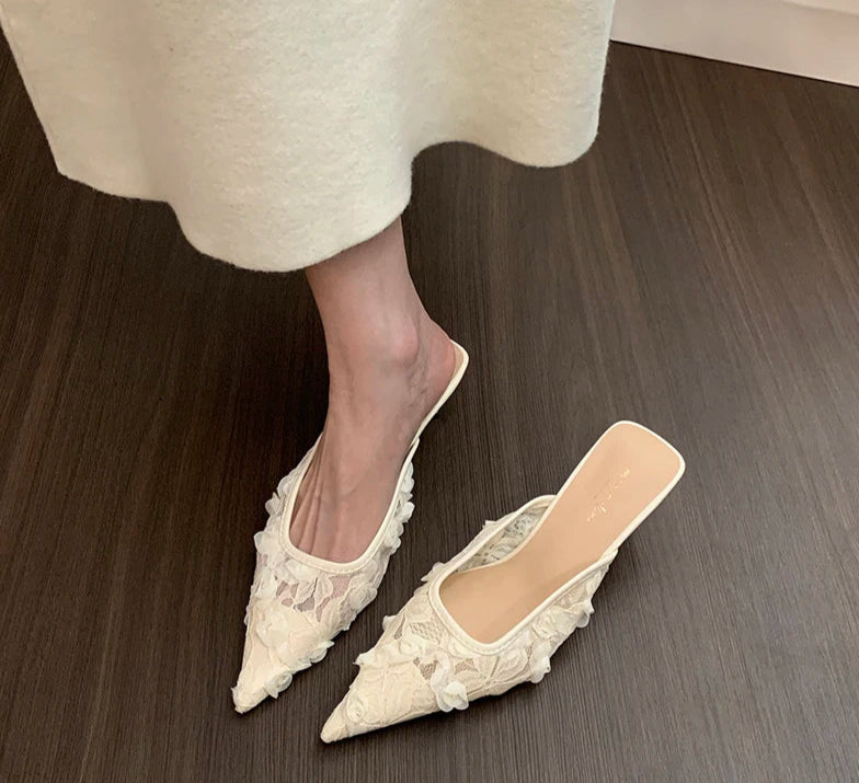 White lace shoes worn with a white skirt on a wooden floor
