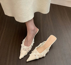 White lace shoes worn with a white skirt on a wooden floor