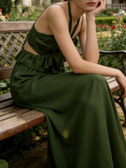 Woman in a green dress sitting on a bench in a garden