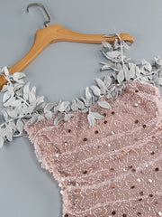 Pink sequined fabric with floral lace trim on a wooden hanger against a gray background