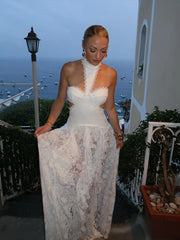Woman in a white lace dress standing on a balcony with ocean view