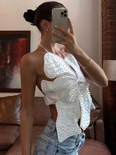 Person wearing a white blouse with butterfly sleeves in a room.