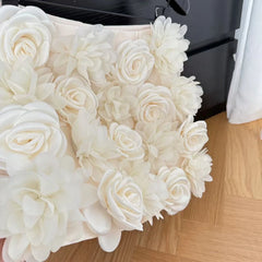 White floral arrangement on a wooden floor with a black object in the background