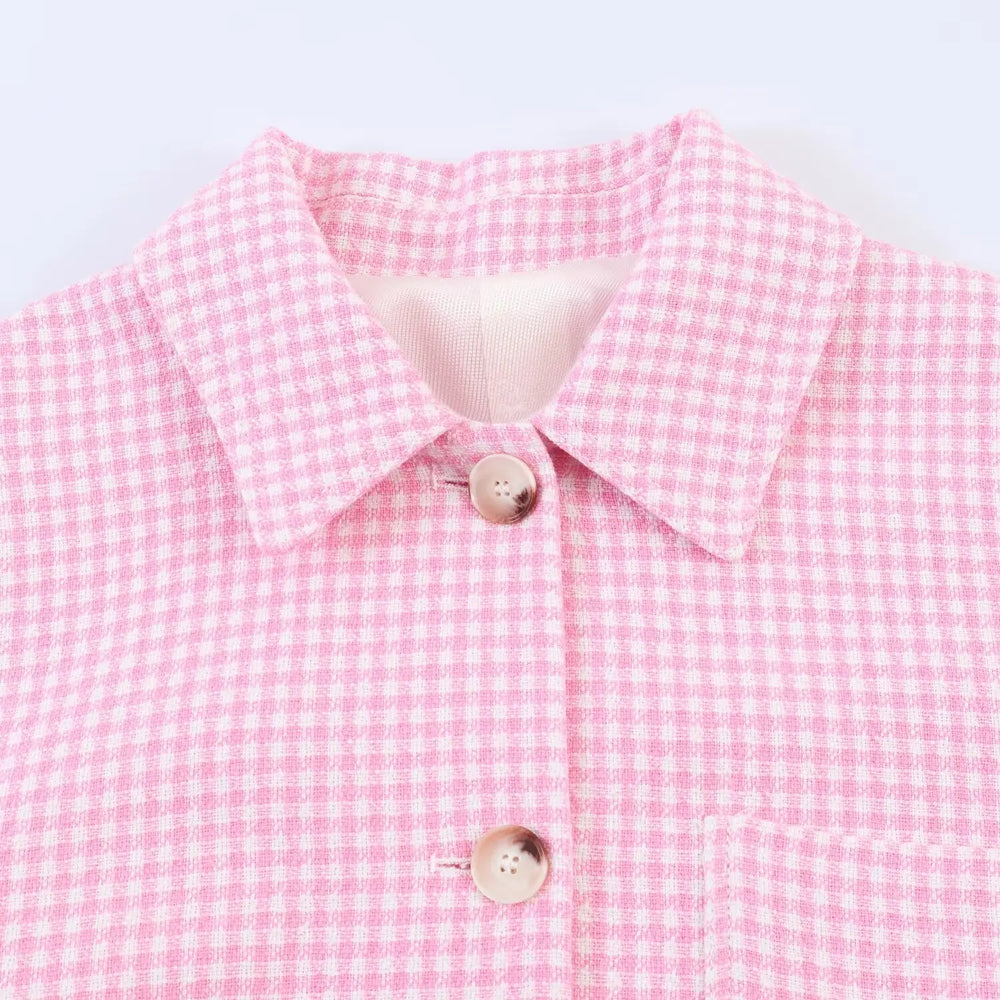 Close-up of a pink checkered shirt with a white collar on a light gray background