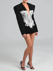 Person wearing a black blazer with lace design on a gray background