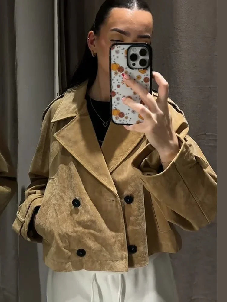 Person wearing a beige trench coat taking a mirror selfie.