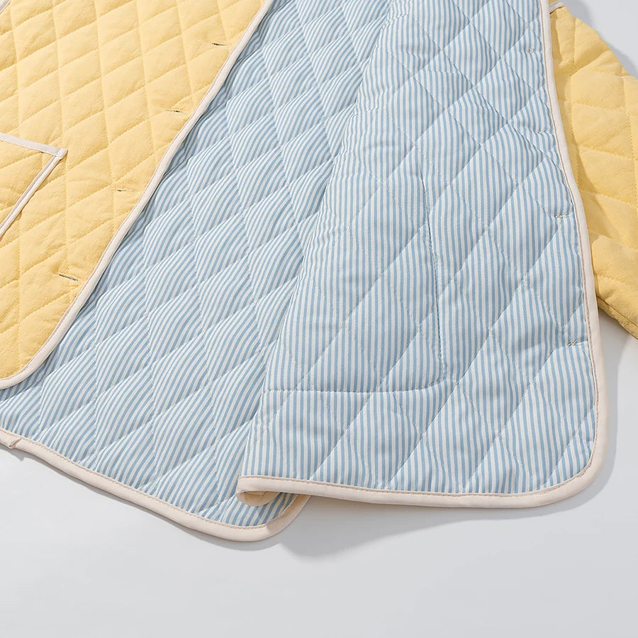 Quilted baby blanket with blue and white striped pattern and yellow borders on a light gray background