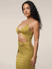 Woman wearing a mustard yellow dress with cut-out design on a beige background