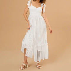 Woman wearing a white lace dress against a beige background