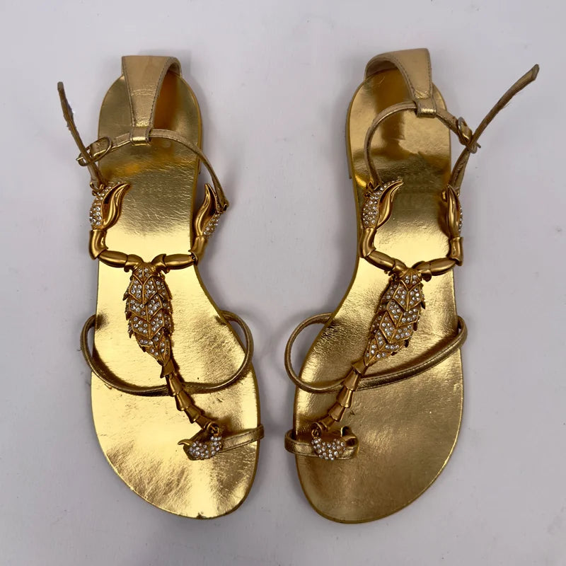 Pair of gold flat sandals with scorpion embellishment