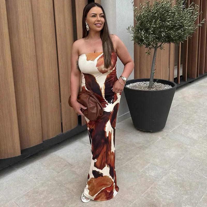 Woman in a strapless dress with a cow print pattern standing outdoors next to a potted plant.