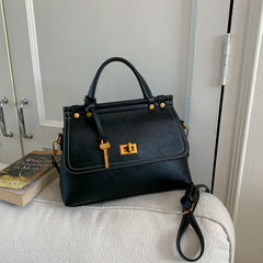 Black handbag with gold accents on a white surface