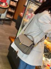 Person holding a gray handbag in an indoor setting